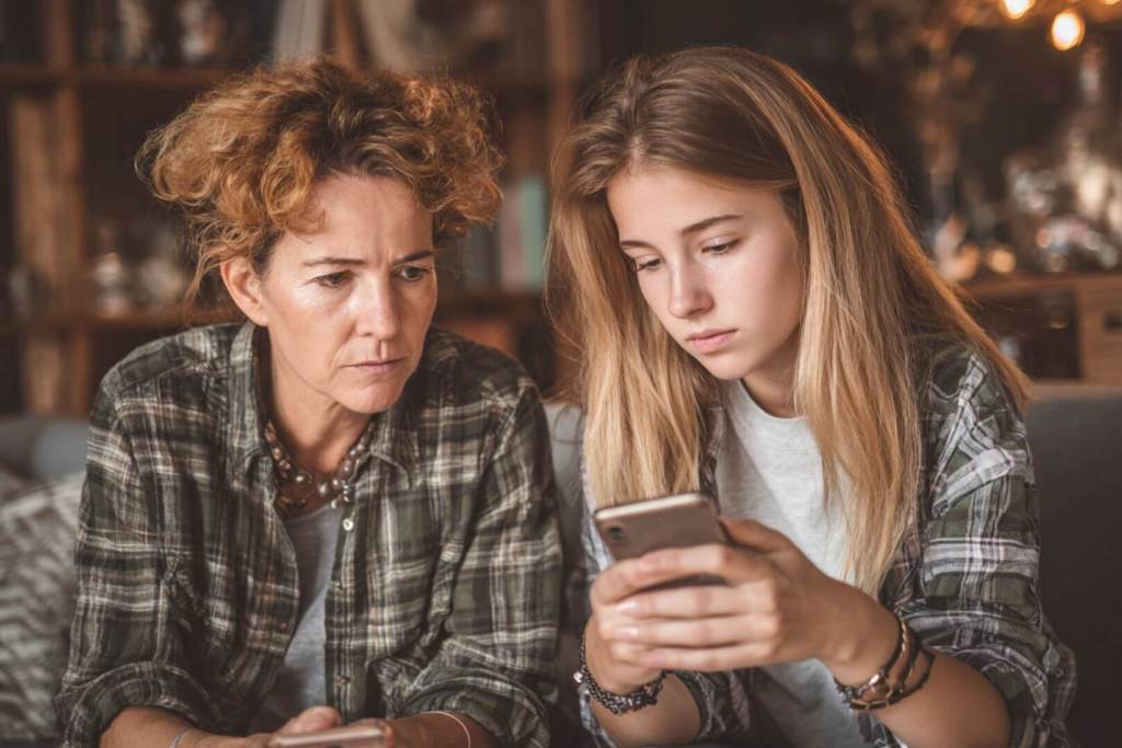 Madre e hija observan juntas la pantalla del móvil, compartiendo un momento de atención y diálogo.