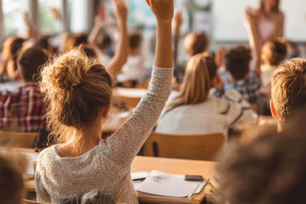 estudiantes en clase levantando la mano para participar durante una lección.
