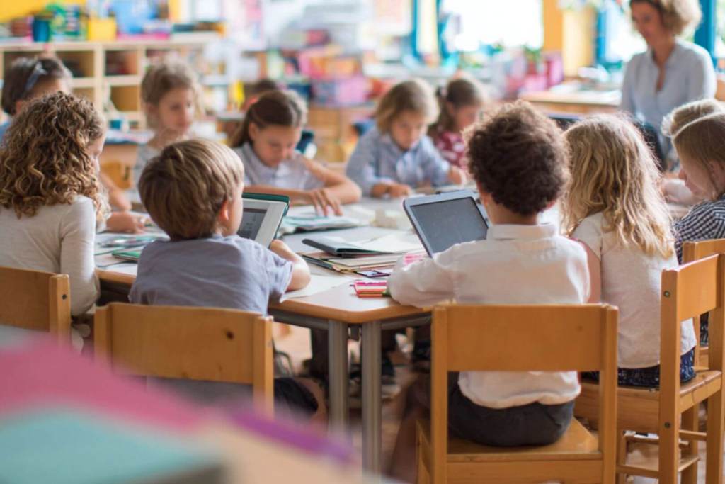 estudiantes en clase levantando la mano para participar durante una lección.