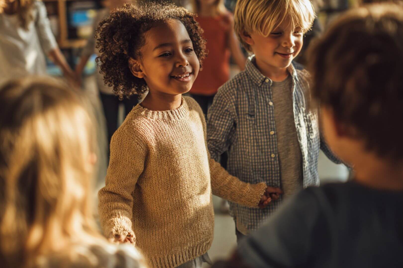 Niños y niñas de infantil cogidos de la mano y sonriendo en clase durante la vuelta al cole.