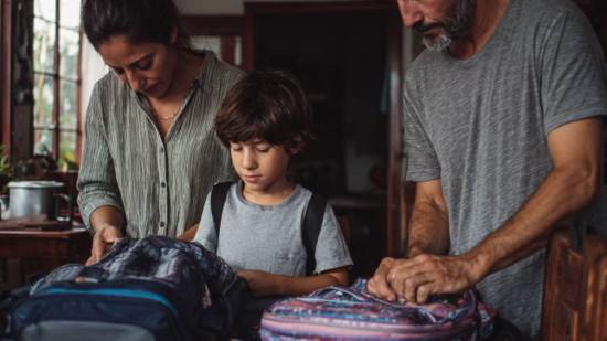 Familia preparando mochilas escolares antes del inicio del curso.